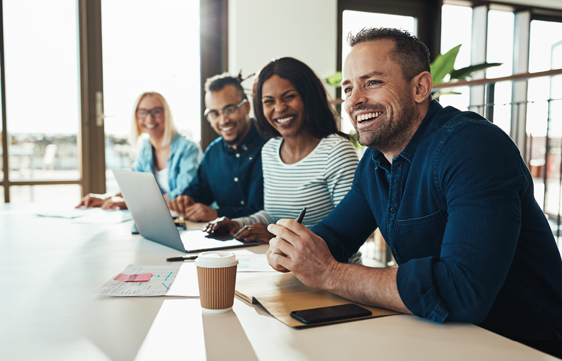 Four Coworkers Smiling at Desk